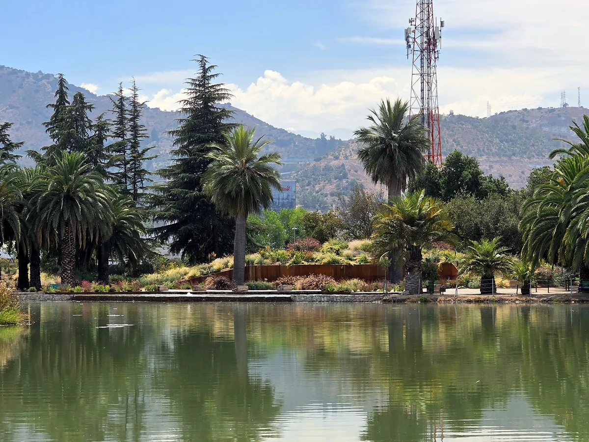 Laguna El Sol del Parque del Recuerdo: espejo de agua con palmeras y la cordillera al fondo