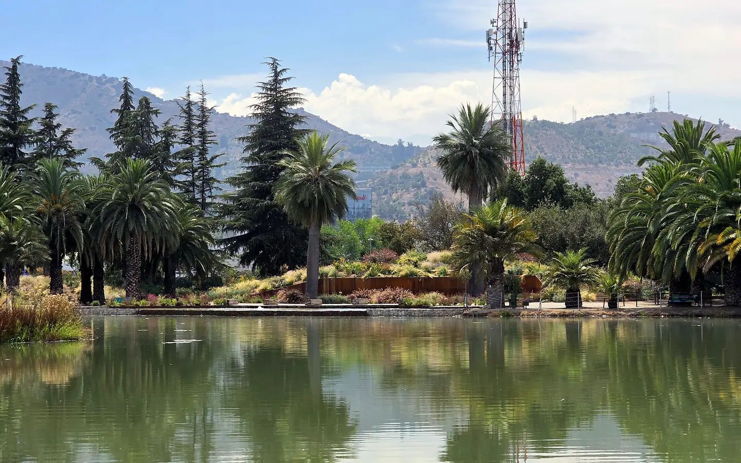Laguna El Sol del Parque del Recuerdo: espejo de agua con palmeras y la cordillera al fondo